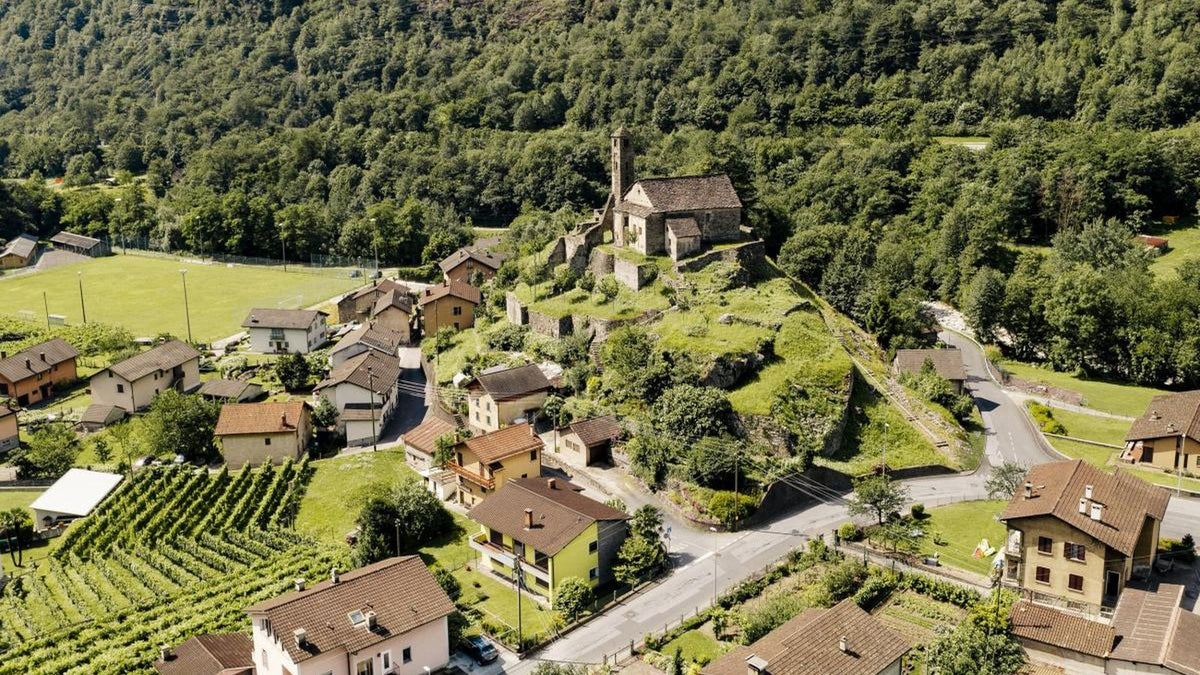 Giornico, vigneti e chiesa in pietra nel paesaggio della Leventina.
